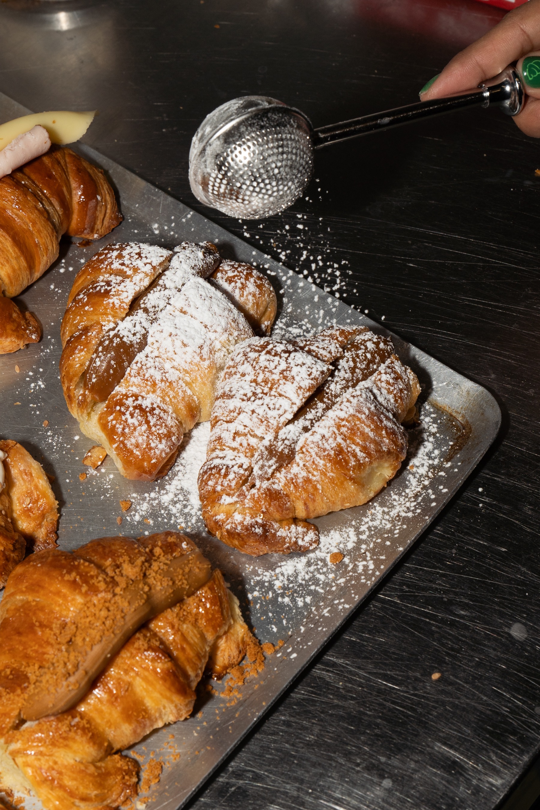Fresh medialunas being dusted with icing sugar at Pancita